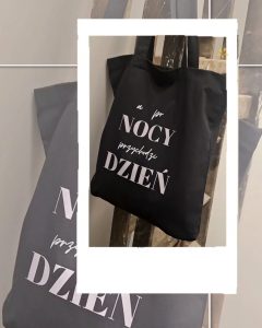 Zdjęcie przedstawia czarną materiałową torbę z napisem